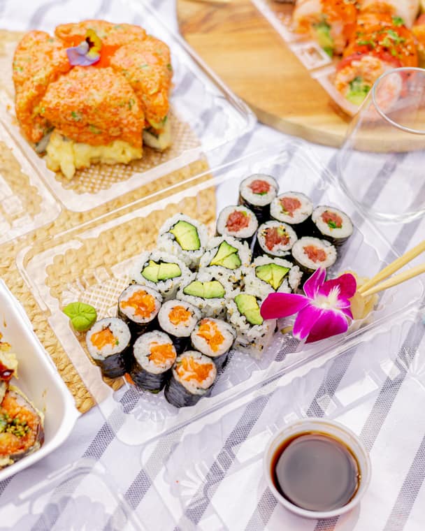 Takeout box of maki rolls and pressed sushi with soy sauce