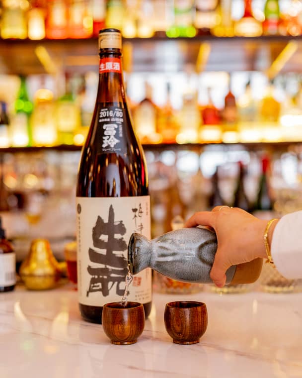 Sake poured into small cups at the bar