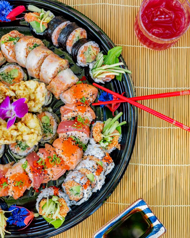 Large round sushi platter with red chopsticks