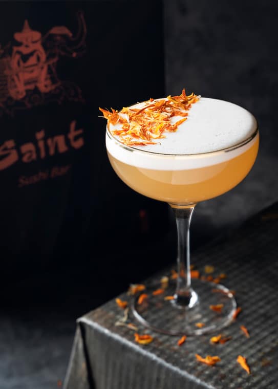 Foamy cocktail garnished with citrus zest